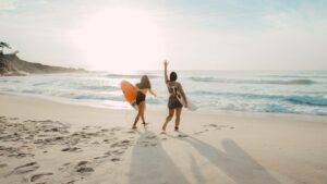 Girls having fun at the beach surfing on a sunny day